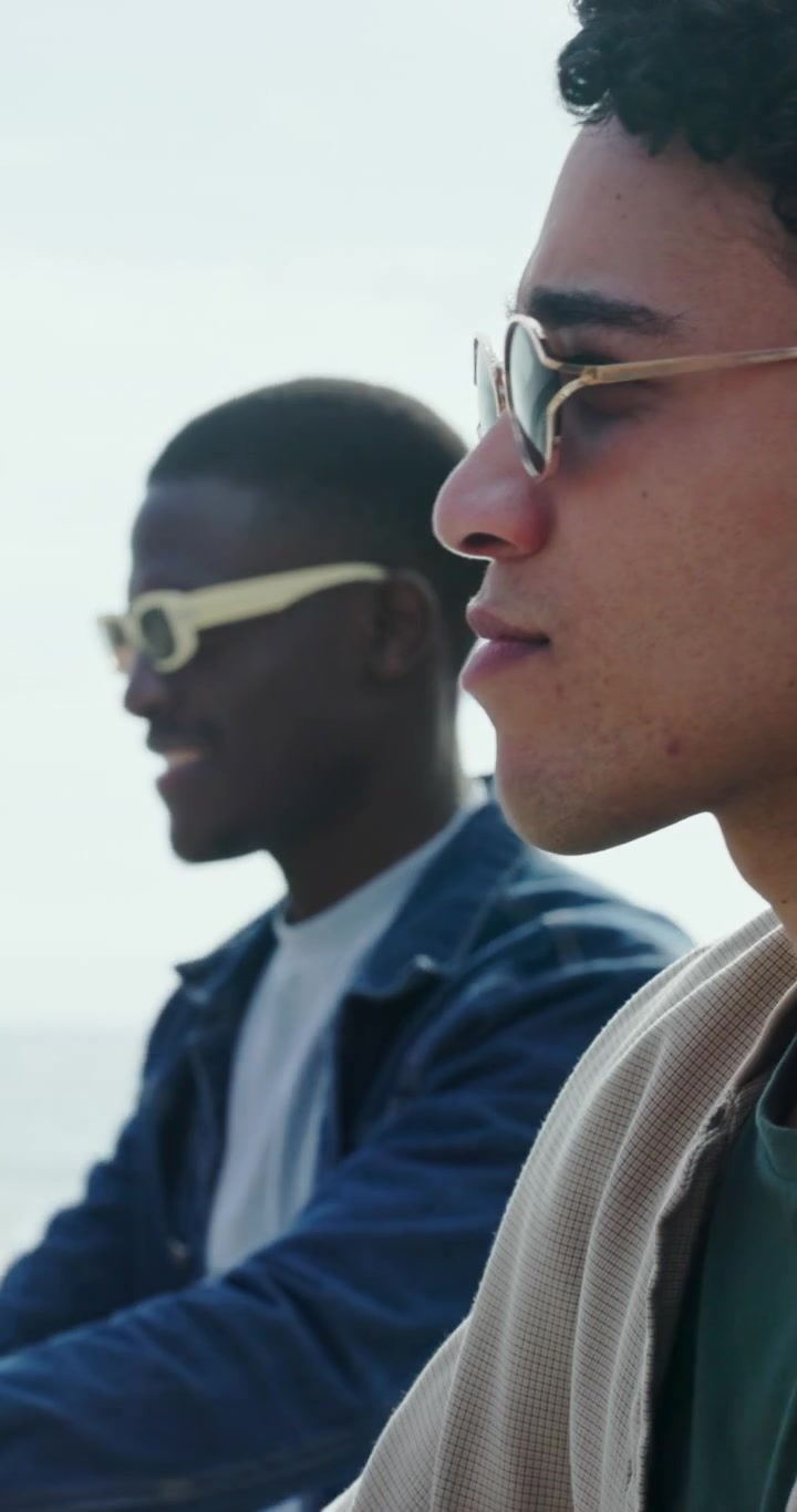 Two Young Men Smiling and Talking Outdoors by the Ocean