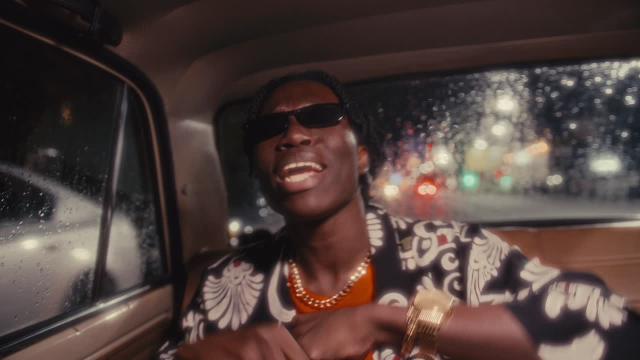 Black Man Riding in Backseat of Car and Rapping to Camera