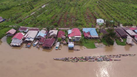 Wooden-boats-full-of-food-pulled-by-a-motorboat-at-Lok-baintan-floating-market,-aerial