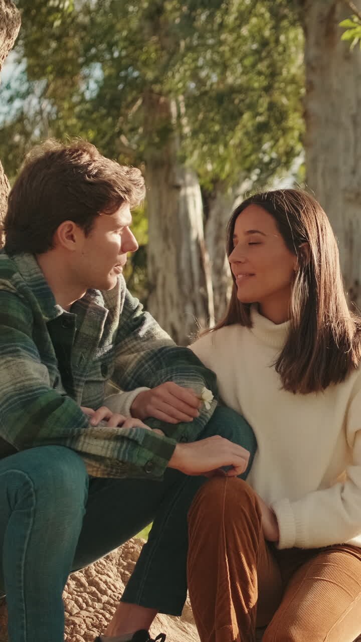 Happy young young pair man and woman relaxing sitting in park under tree