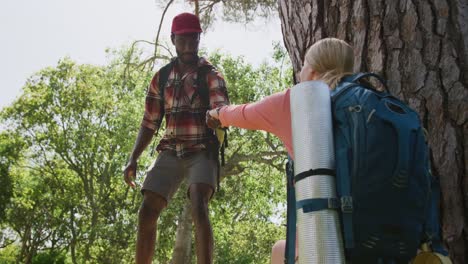 Happy-diverse-couple-hiking-with-backpacks-in-park,-slow-motion