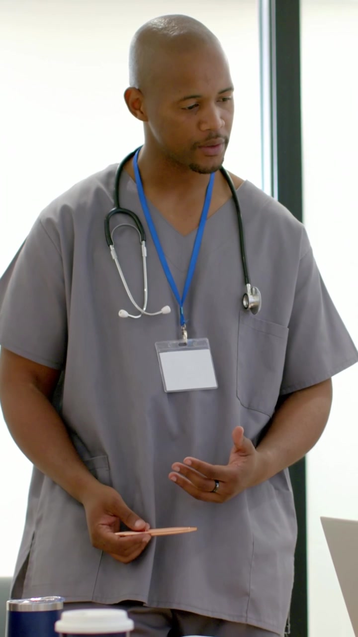 Video verticale: Reagendo a un segnale fuori campo, medico che usa una penna in clinica, con camice grigio e stetoscopio.