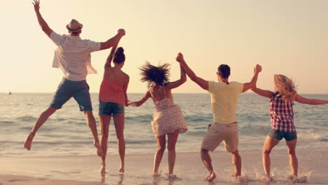 group of friends jumping together on the beach