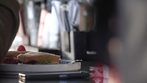 slow motion - hand of person with sandwich placed on white plate on table