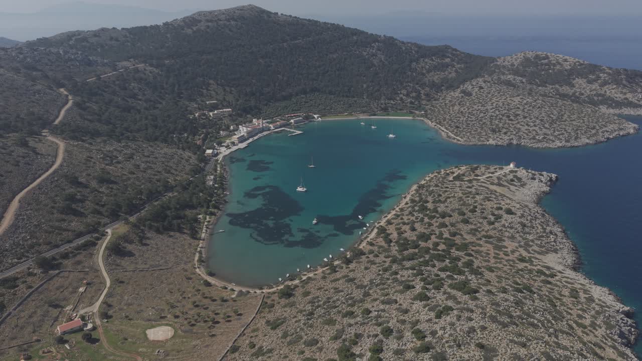 Professional aerial footage documenting the beautiful Panormitis Monastery on Symi island. The drone captures the spiritual sanctuary's unique position nestled between mountains and sea. D-Log M