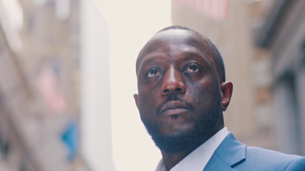 New York, USA, 1 May 2024: Close up portrait of man in light blue suit on urban street. Soft backlight with shallow depth of field and blurred city backdrop.