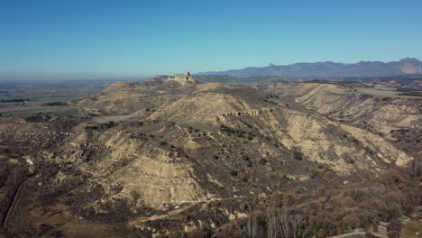 aerial view of a historical hilltop fortress in a dry mountainous landscape