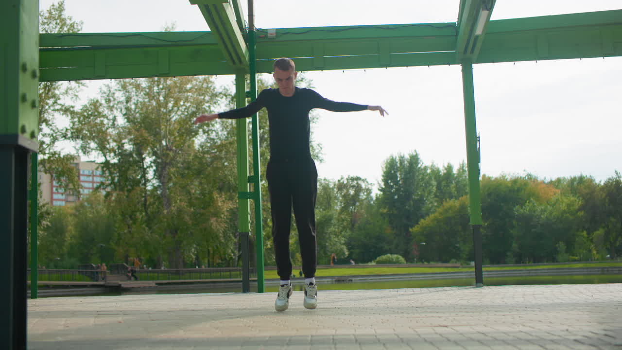 Uomo bianco che salta sotto una tettoia verde, movimenti freestyle aerei ed equilibrio sicuro sui pattini, parco urbano sullo sfondo con lago e alberi, primi piani del movimento ed espressione concentrata durante l'addestramento