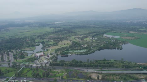 Dolly-Inn-Con-Jib-Abajo-Sobre-La-Carretera-Con-Acercamiento-A-Un-área-Natural-Y-Un-Lago-En-Xochimilco,-Ciudad-De-México