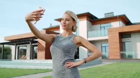 Smiling-woman-making-selfie-near-apartment.-Closeup-blonde-woman-taking-photo