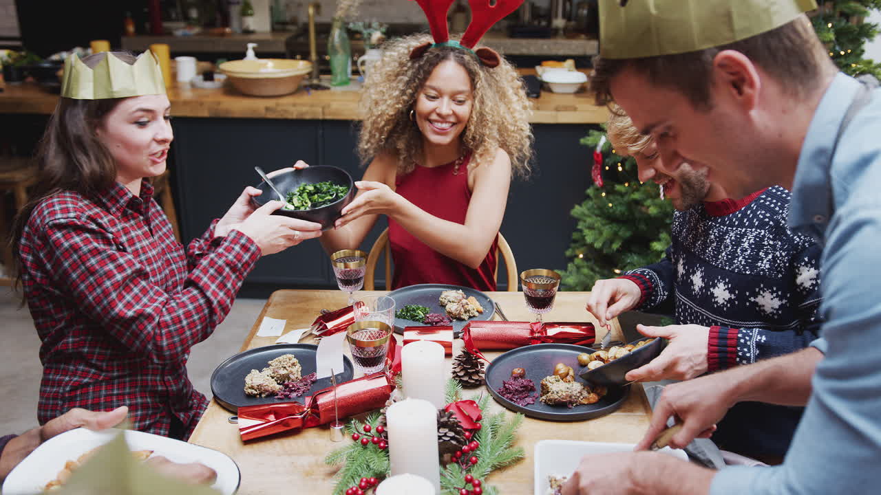grupo de amigos sentados alrededor de la mesa de comedor en casa mientras se sirve la cena de navidad vegetariana