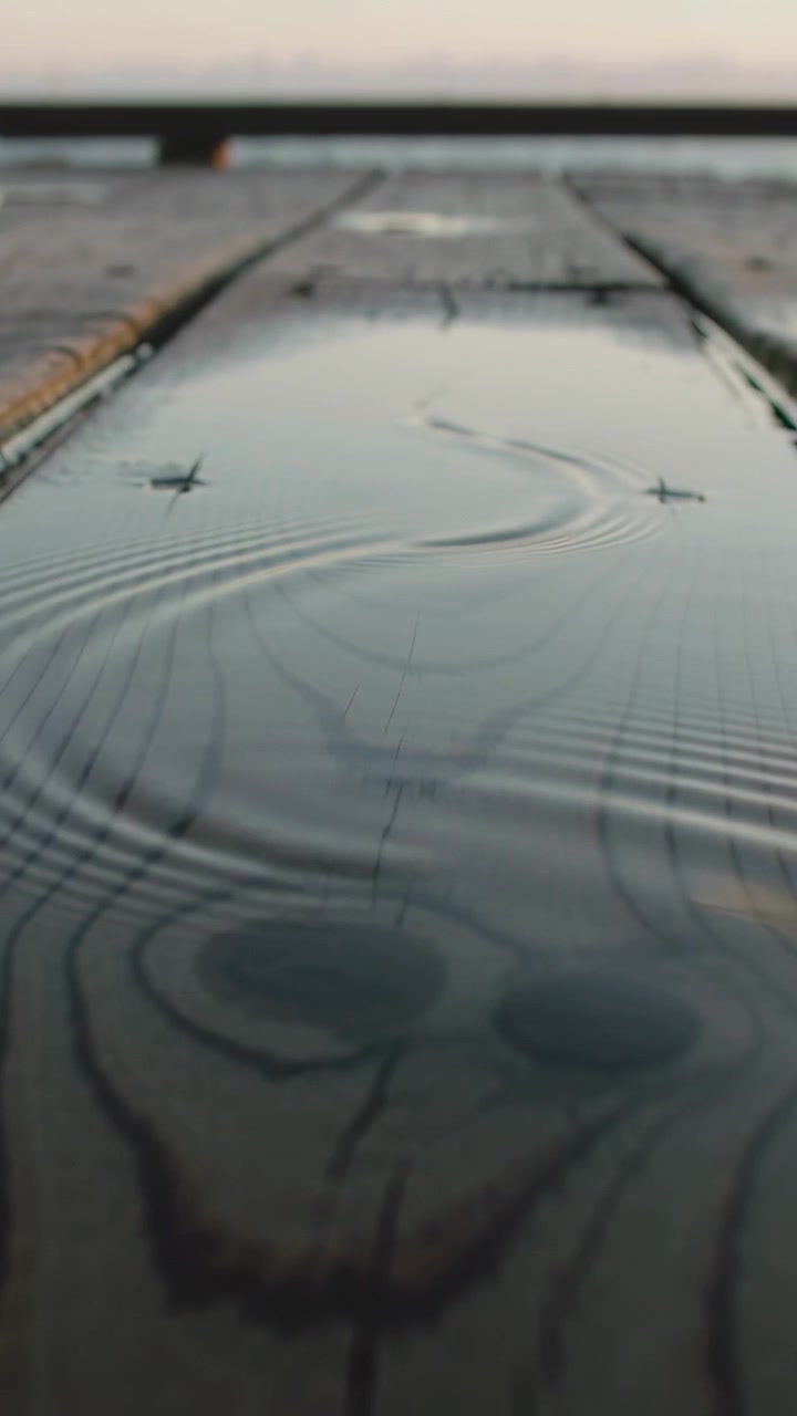 Vertical video: Starting disturbance sending S wake and expanding ripples past pegs on dock