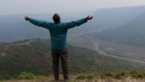 hombre disfrutando de la naturaleza en la cima de la colina con el fondo de la furia de la montaña brumosa desde un video de ángulo plano tomado en nongjrong meghalaya india