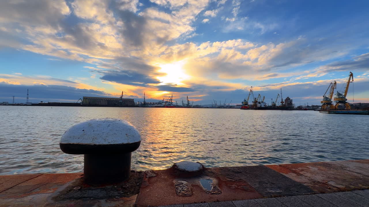 Sunset at the harbor with ships and clouds in the sky over the water. The sun sets over a harbor filled with ships and clouds
