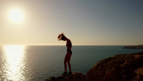 woman preparing for and executing a cliff dive into the ocean