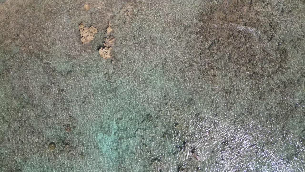 imágenes de drones volando sobre un océano azul tropical siguen las olas en la costa mientras rompen un arrecife de coral en el caribe