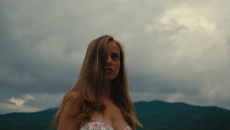 woman in a floral dress, outdoors in a scenic mountain landscape