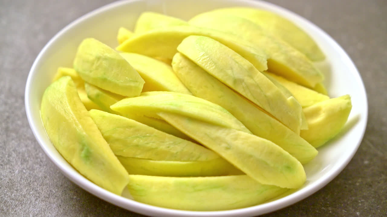 mango verde fresco y dorado en rodajas en un plato
