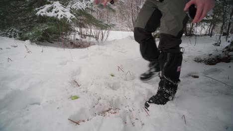 man scattering seeds in the snow in a mountain village