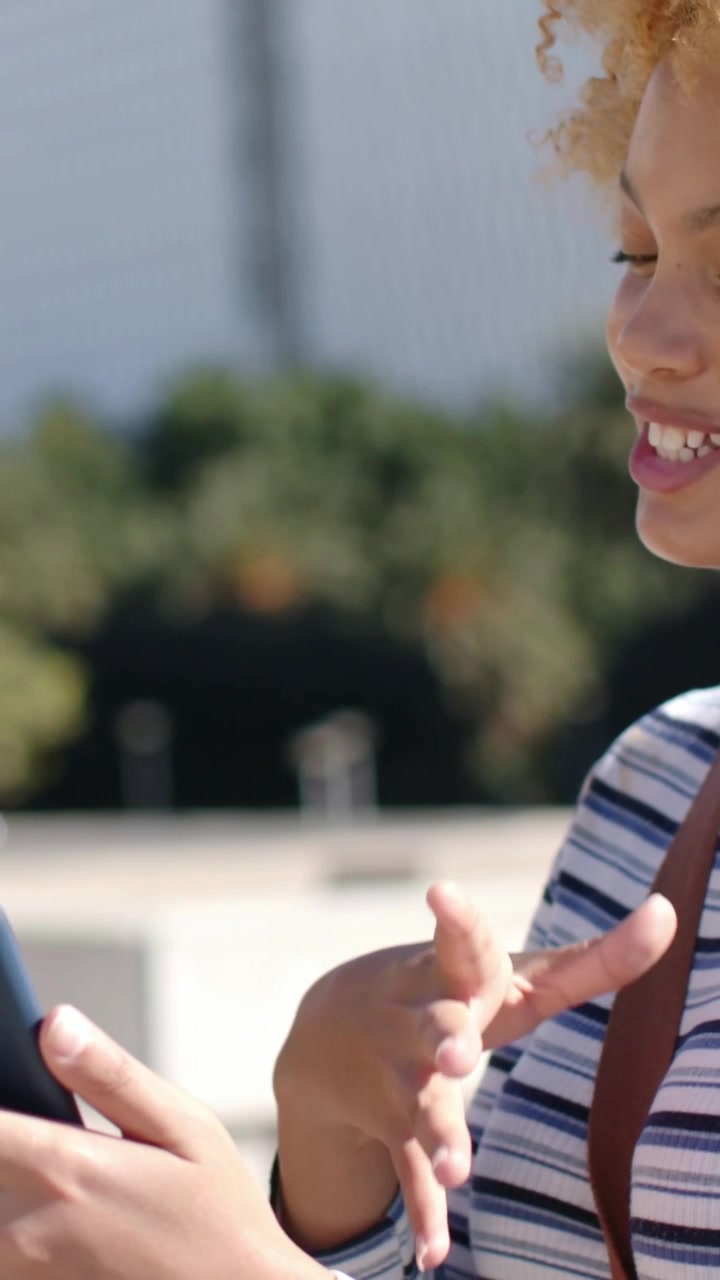 Vertical video: Opening with female tapping smartphone, male carrying backpack in plaza, copy space