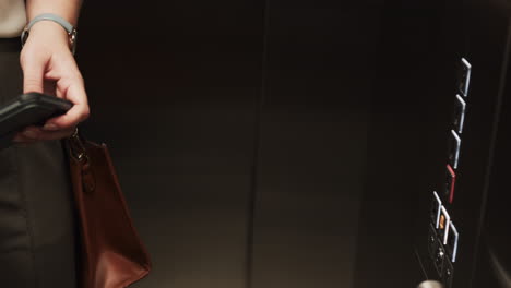 holding briefcase, person pressing elevator buttons in office building