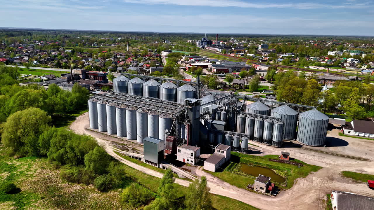 Large industrial silos stand near a small village, blending industry with surrounding nature.