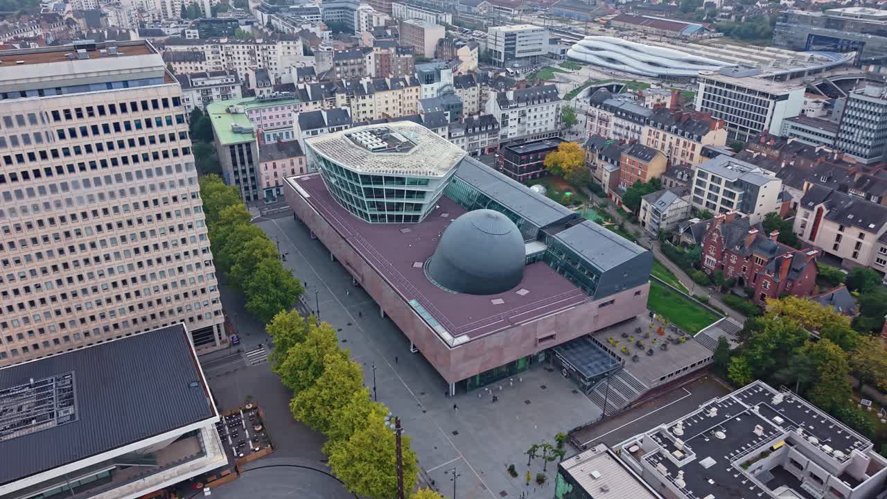 Drone shot pulling back and panning left to right over Les Champs Libres in Rennes, showing the cultural complex and surrounding cityscape