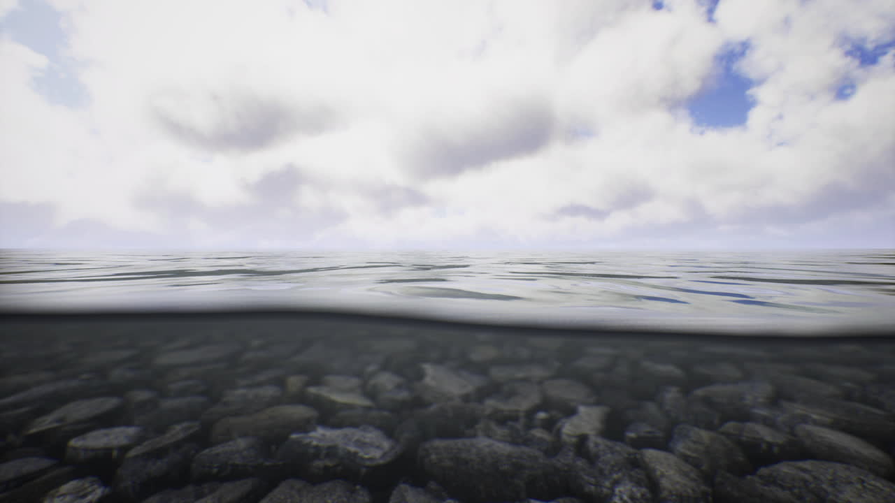 Clear water reveal in serene lake with rocky bottom under soft clouds