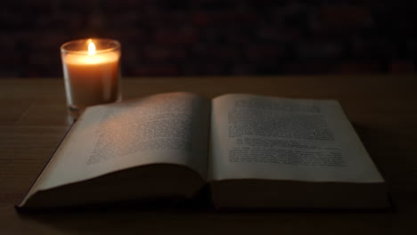 encendiendo una vela al lado de un libro viejo en un cuarto oscuro