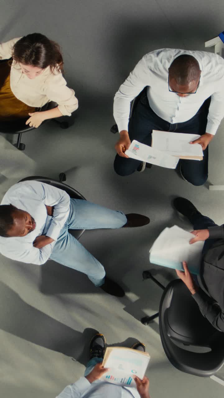 Vertical Video Top down view zoom in of employees discussing targets and objectives