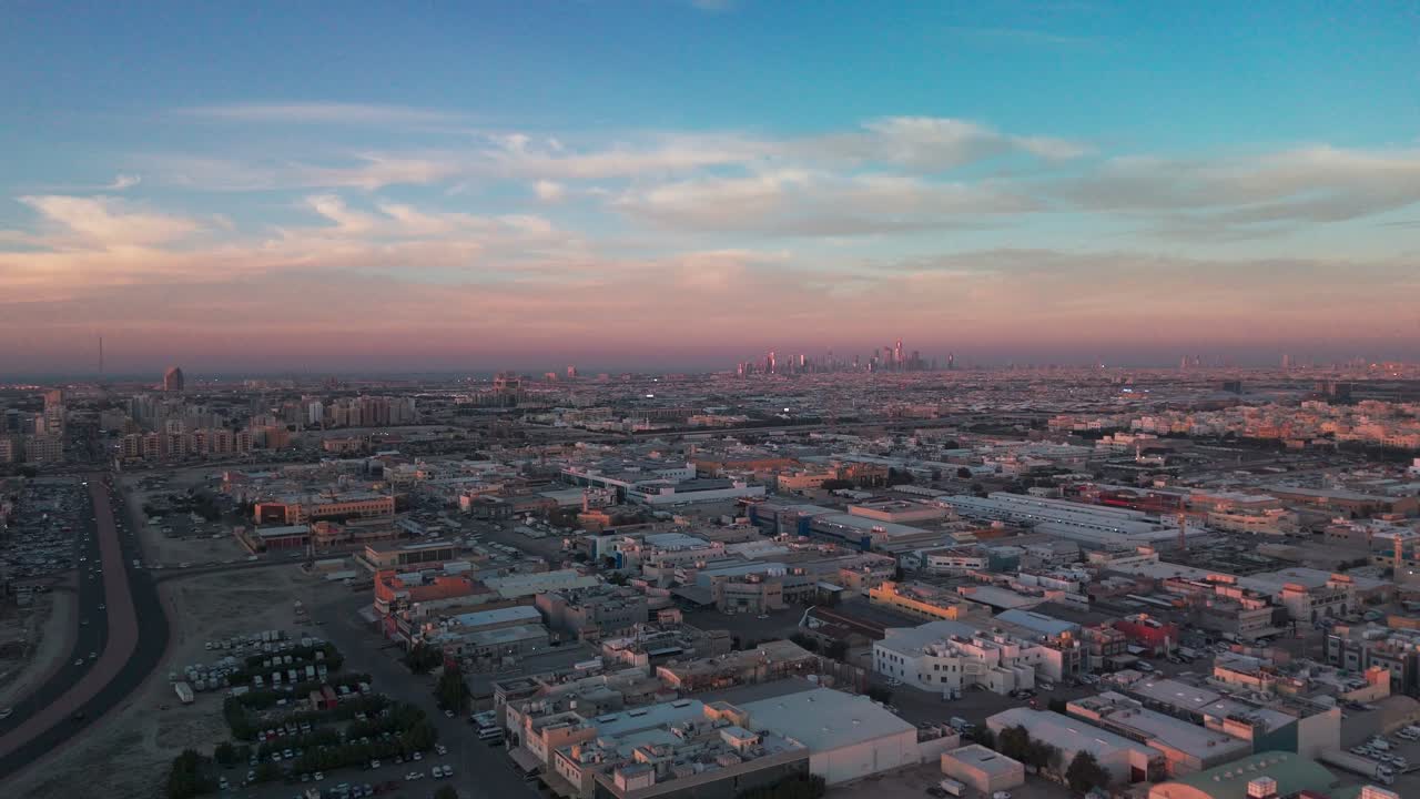 Ampia ripresa aerea con drone di una vasta metropoli nel deserto durante l'ora d'oro, con grattacieli downtown in lontananza, autostrade e tetti sotto nuvole color pastello e la calda luce del tramonto