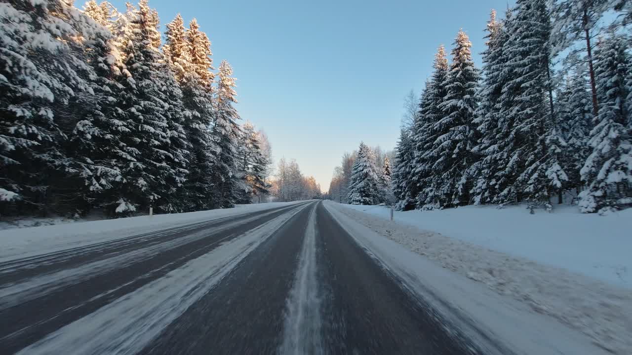 Speeding along winter roads through Finlands forest landscape sunny day POV