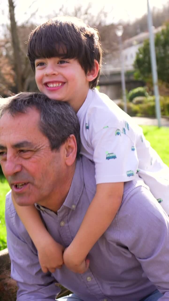 Grandfather and grandson piggybacking in a park