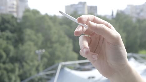 woman's hand holding a cigarette smoke coming out. close up