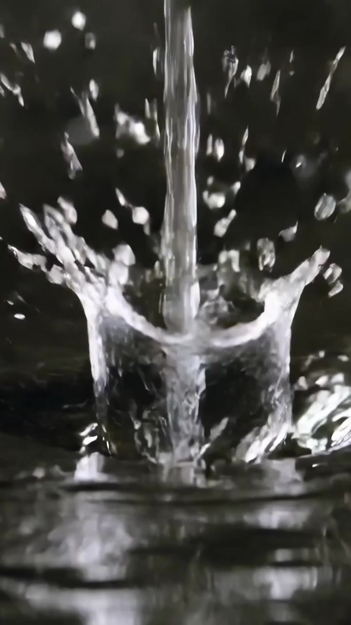 Video verticale: Goccia che impatta creando un getto di rimbalzo in una vasca da studio, formando una corona e satelliti.