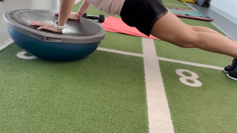 fit woman performs controlled flexion exercises on a balance ball, showcasing strength and balance