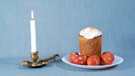salida de la cámara, arreglo de pascua, pascua en el plato blanco con huevos teñidos, cerca de la vela blanca ardiente