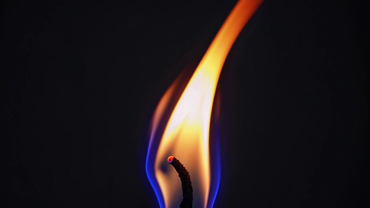 Close-up of a Single Candle Flame Burning in the Dark