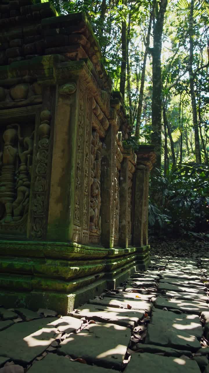 Low-angle shot of ancient stone carvings in a lush jungle setting, perfect for a video exploring