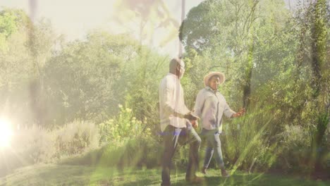 video of lights over biracial senior couple walking in nature