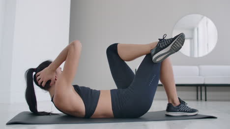 caucasian brunette woman doing abs exercise while lying on a carpet. daily workouts at home for a healthy body.