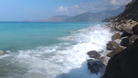 Sea-waves-splashing-on-cliffs-of-natural-beach,-washing-the-sand-with-white-foam-in-Mediterranean-coast