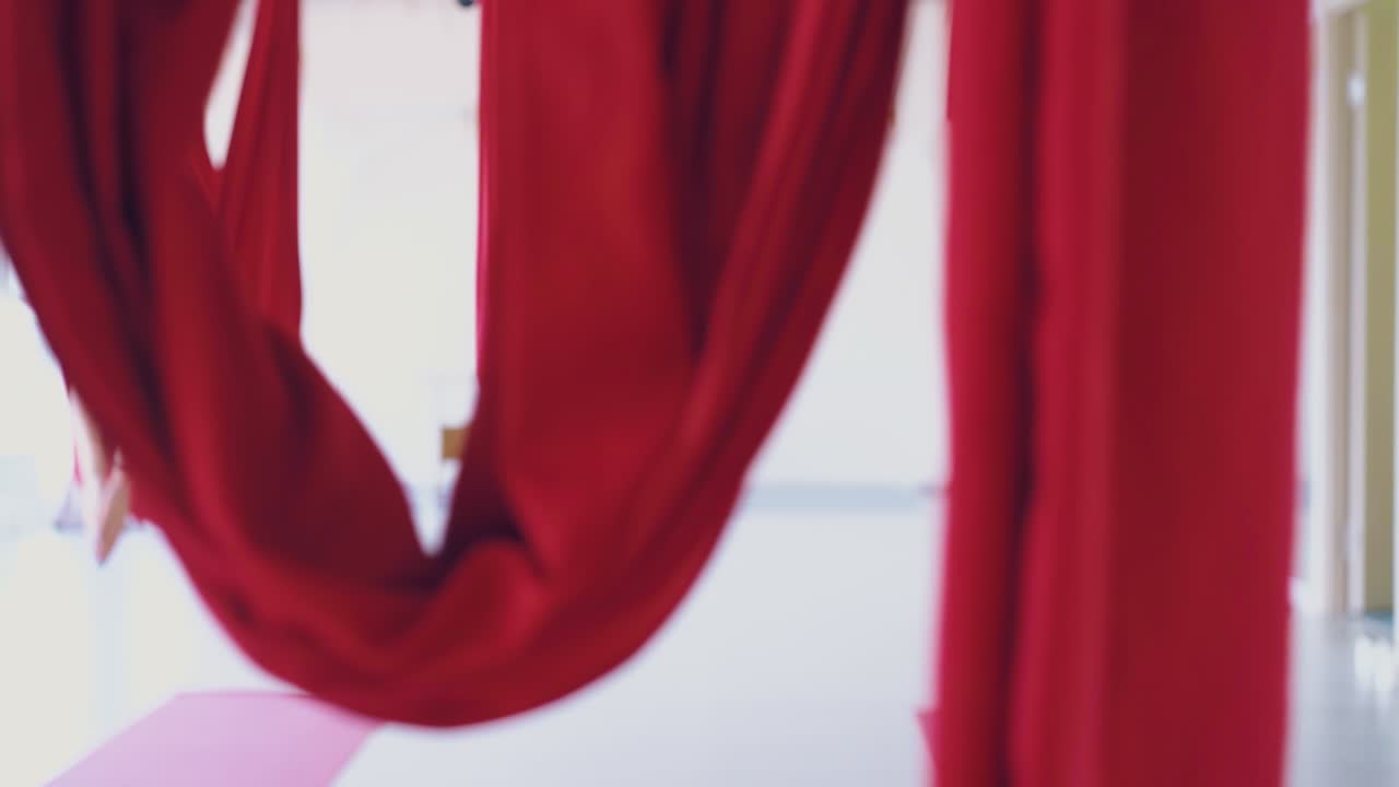 женщины лежат в красных гамаках и восстанавливают энергию после летающей йоги