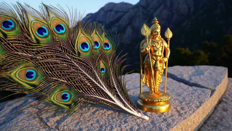 aayappan statue with peacock feather, mountain background