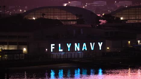 fly navy sign lit up at night with glowing blue lettering