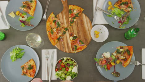 overhead view of friends in pizza restaurant taking picture of food on mobile phone