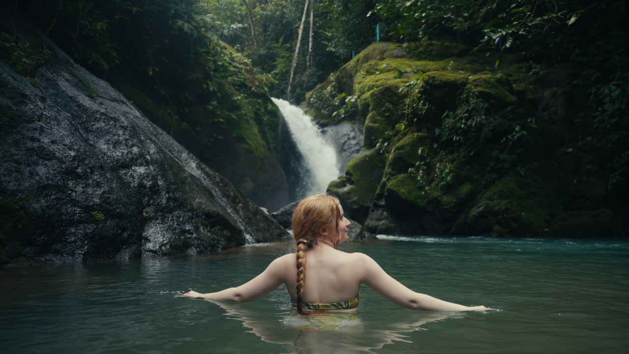 Woman swimming in a tropical waterfall