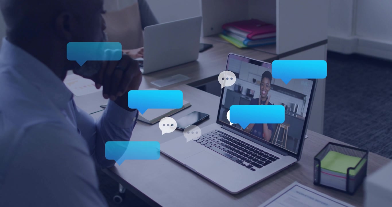 Uomo d'affari che avvia una chiamata con una collega per chattare, mostrando bolle di chat che si formano intorno al laptop.