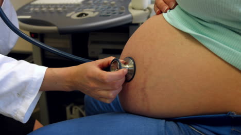 doctor using a stethoscope on a pregnant womans stomach