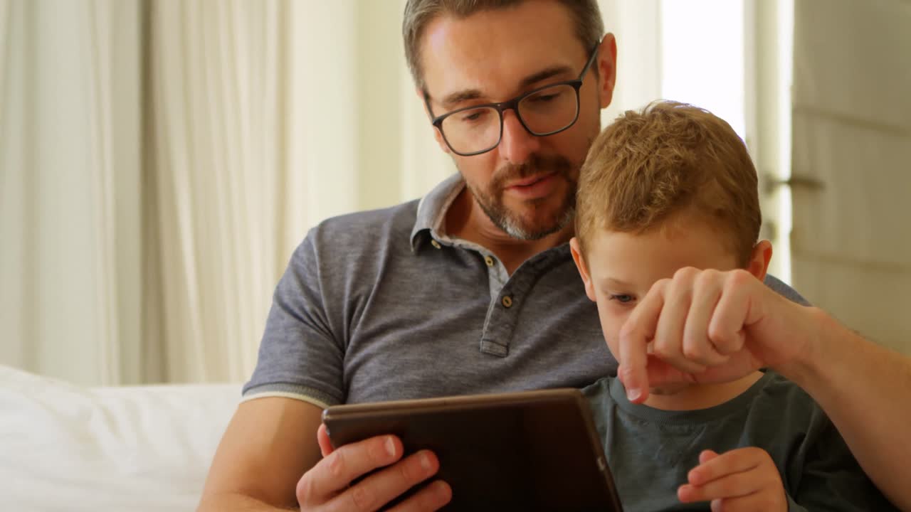 padre e hijo usando tableta digital en el sofá en casa 4k